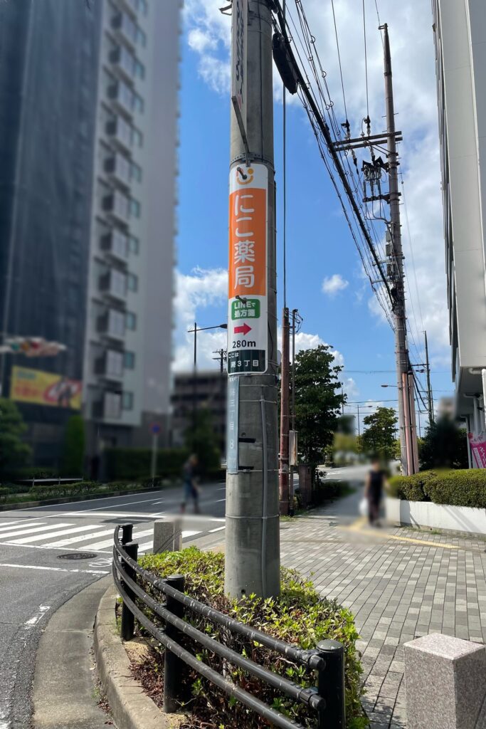 にこ薬局 案内看板 栗東駅東口の交差点に設置 電柱の矢印看板