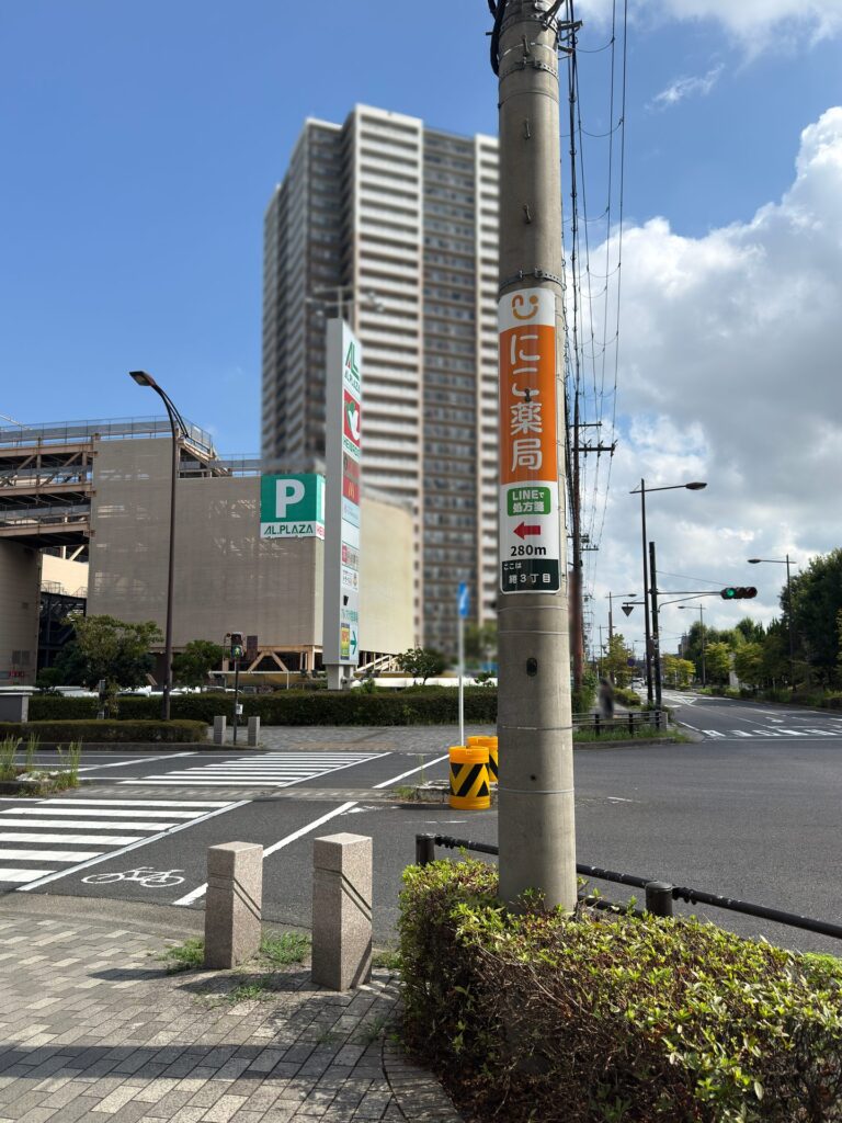 にこ薬局 案内看板 栗東駅東口の交差点に設置 電柱の矢印看板
